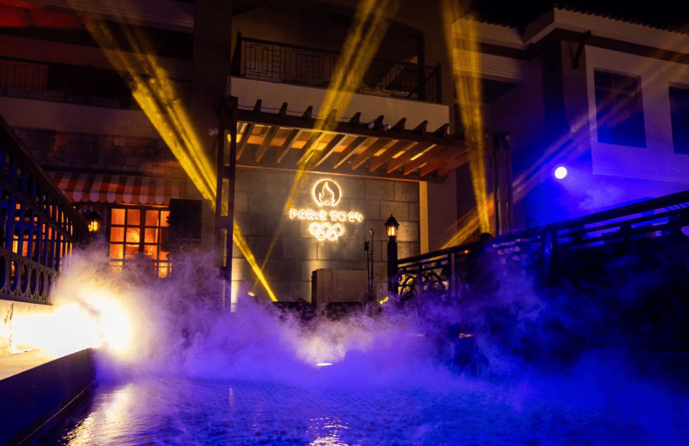 Night scene with mist and lights showcasing Paris 2024 Olympic logo on building facade.