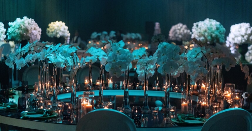 Elegant dinner setting with candles and white flowers on a circular table, creating an intimate evening ambience.