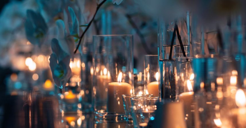 Elegant candles and glass vases create a warm, intimate ambiance with soft lighting and floral reflections.